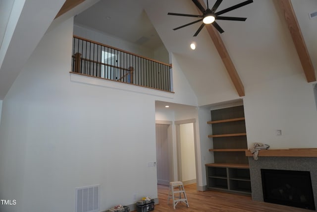 unfurnished living room featuring beam ceiling, visible vents, a fireplace, and wood finished floors