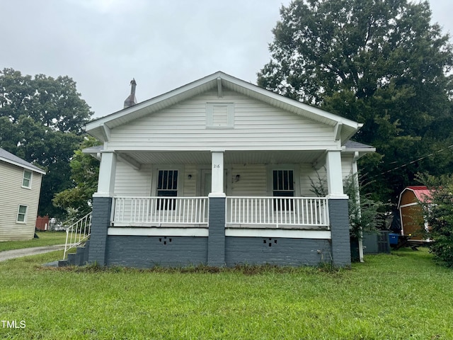 bungalow-style house with a front yard and covered porch