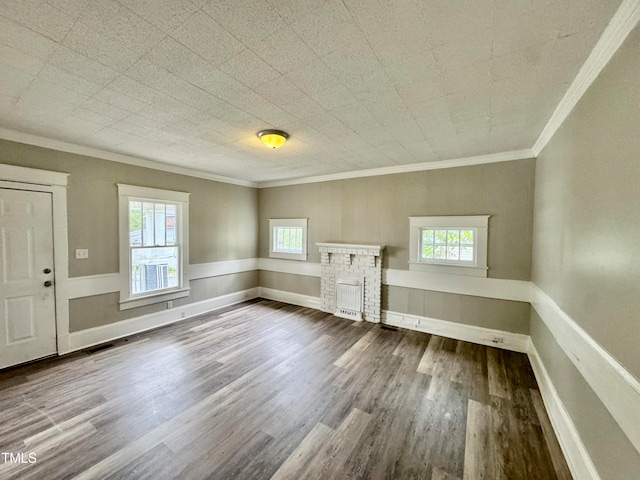 unfurnished living room with ornamental molding, hardwood / wood-style flooring, a healthy amount of sunlight, and a stone fireplace