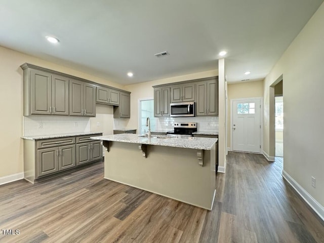 1005 Sunnybrook Rd S, Wilson, NC 27893 - kitchen with a breakfast bar area, light stone countertops, appliances with stainless steel finishes, gray cabinetry, and dark wood-style flooring