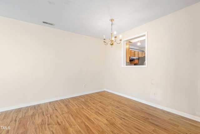 empty room with hardwood / wood-style flooring and a chandelier