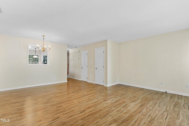 unfurnished room with a chandelier and light hardwood / wood-style floors