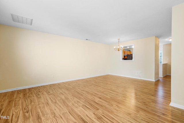 unfurnished room featuring light hardwood / wood-style floors and a chandelier