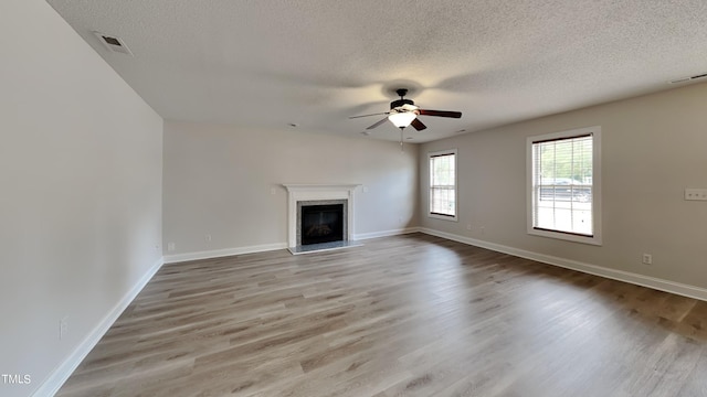 unfurnished living room with a textured ceiling, ceiling fan, and light hardwood / wood-style flooring