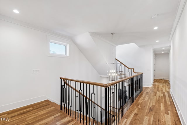 hallway featuring an inviting chandelier, crown molding, lofted ceiling, and hardwood / wood-style flooring