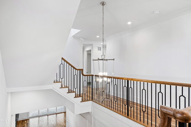 stairway featuring an inviting chandelier, ornamental molding, and wood-type flooring