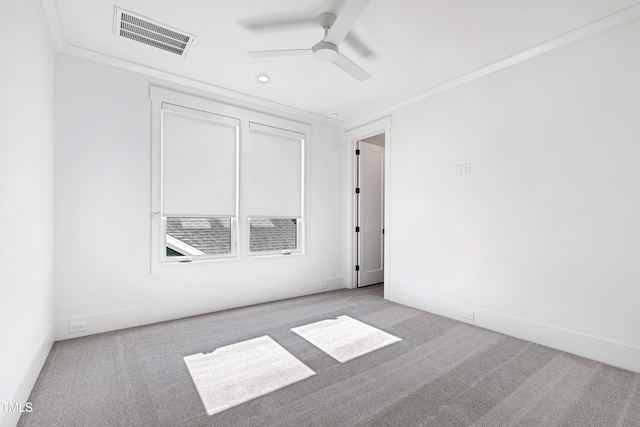 spare room with ceiling fan, crown molding, and light carpet