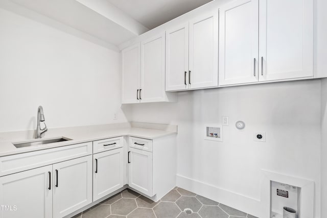 clothes washing area with hookup for an electric dryer, hookup for a washing machine, cabinets, dark tile patterned flooring, and sink