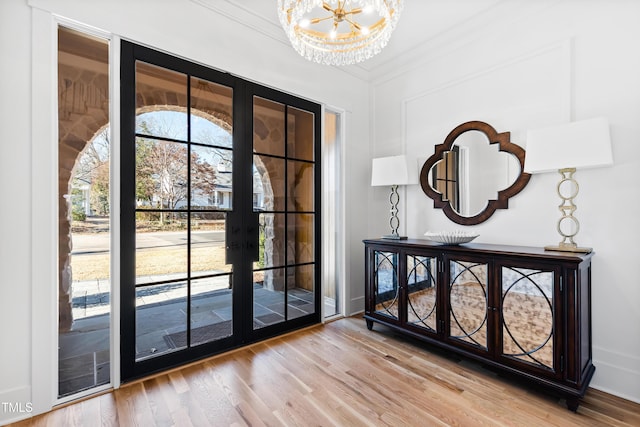 doorway to outside with an inviting chandelier, french doors, crown molding, and hardwood / wood-style floors