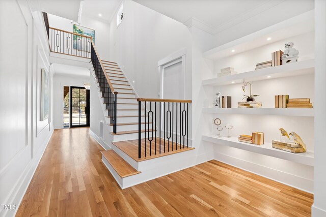 interior space featuring a high ceiling, ornamental molding, and hardwood / wood-style flooring