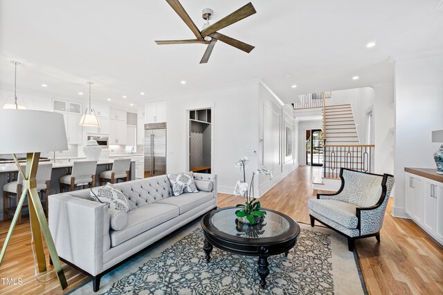 living room with ceiling fan, light hardwood / wood-style flooring, and ornamental molding