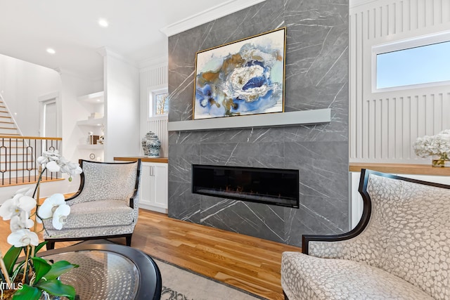 living room with a fireplace, light wood-type flooring, crown molding, and a wealth of natural light