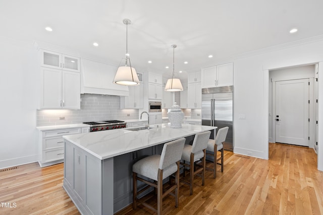 kitchen with sink, white cabinetry, a kitchen island with sink, and appliances with stainless steel finishes