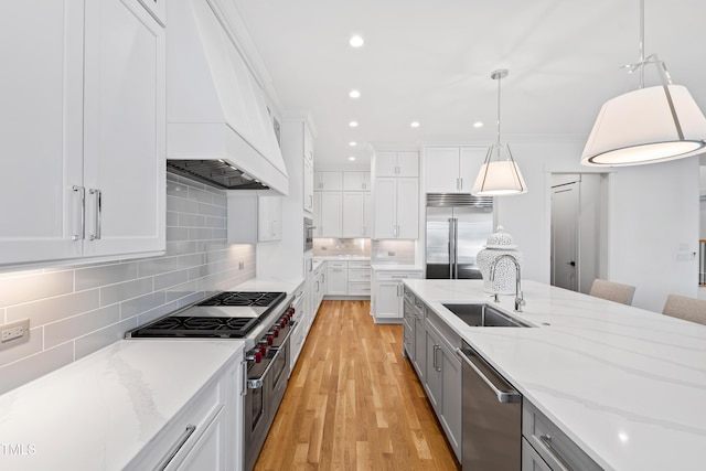 kitchen featuring white cabinets, pendant lighting, high end appliances, and sink