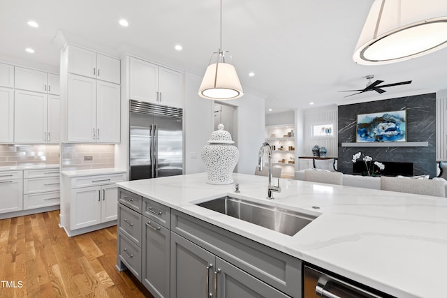 kitchen with light hardwood / wood-style flooring, decorative light fixtures, white cabinetry, appliances with stainless steel finishes, and sink