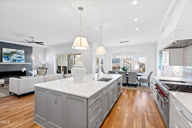 kitchen featuring a center island with sink, ceiling fan, a healthy amount of sunlight, sink, and decorative light fixtures