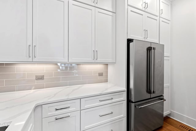 kitchen with white cabinetry, light stone counters, hardwood / wood-style flooring, tasteful backsplash, and high end refrigerator