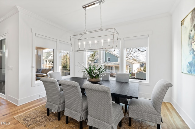 dining area with wood-type flooring, a chandelier, and ornamental molding