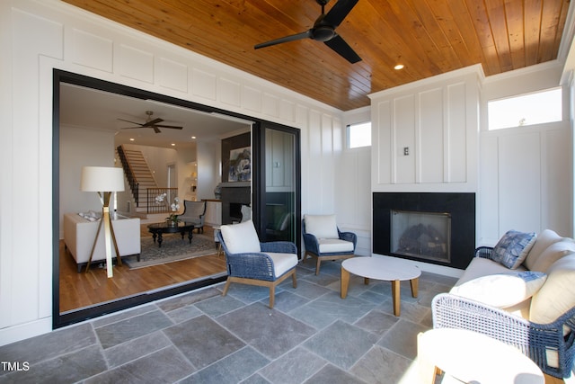 living room featuring a healthy amount of sunlight, ceiling fan, ornamental molding, and wood ceiling