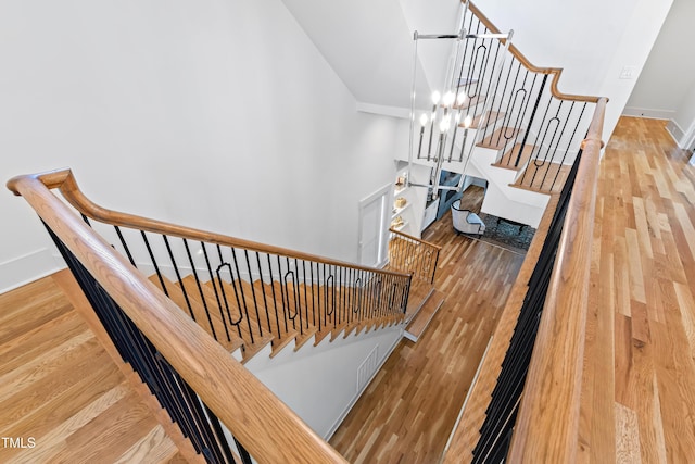 staircase with wood-type flooring and a notable chandelier