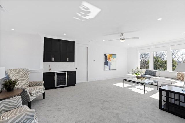 carpeted living room with ceiling fan, indoor bar, ornamental molding, and wine cooler