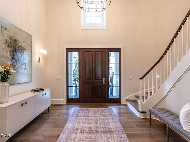 entrance foyer with a towering ceiling, dark wood-type flooring, and a chandelier