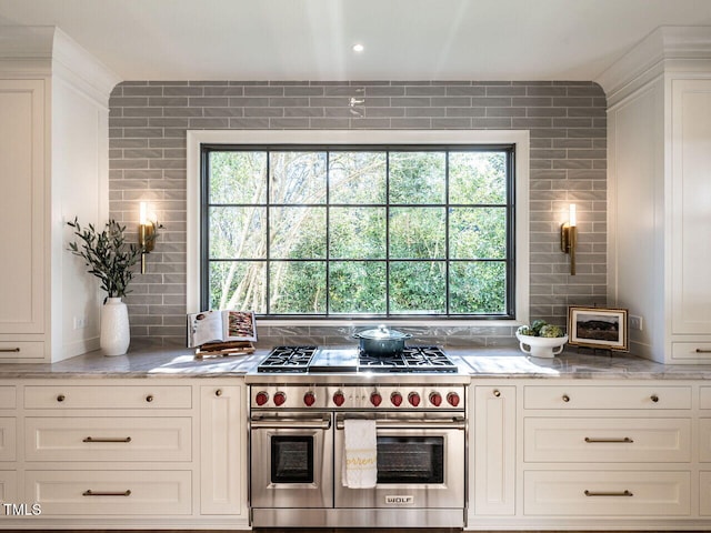 kitchen featuring white cabinets, decorative backsplash, a healthy amount of sunlight, and range with two ovens