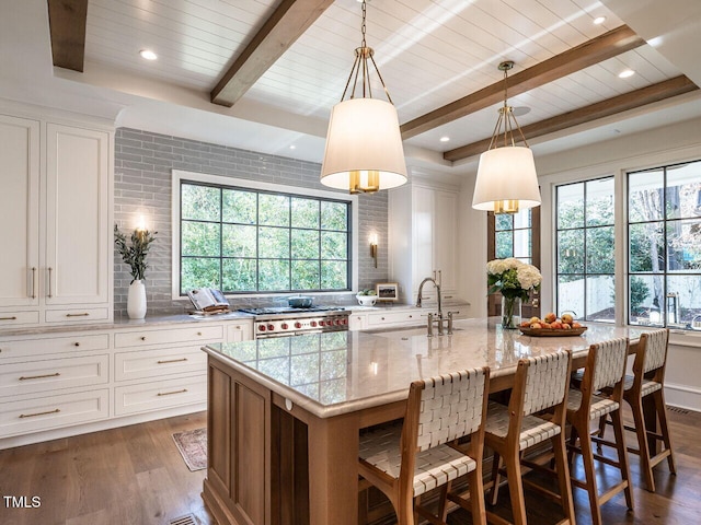 kitchen featuring light stone countertops, dark hardwood / wood-style flooring, a spacious island, sink, and decorative light fixtures