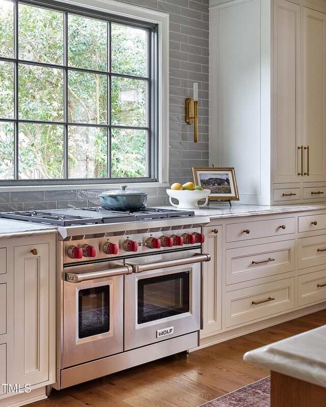 1307 Mayfair Rd, Raleigh, NC 27608 - kitchen with double oven range, wood finished floors, white cabinetry, and light stone counters