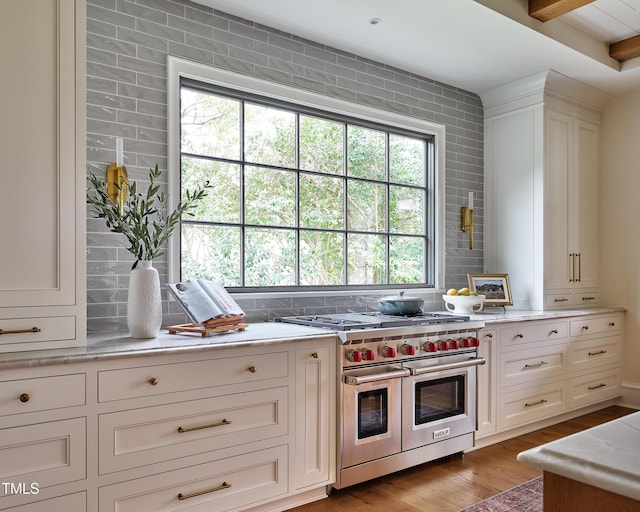 1307 Mayfair Rd, Raleigh, NC 27608 - kitchen with double oven range, healthy amount of natural light, light wood-style flooring, and white cabinetry