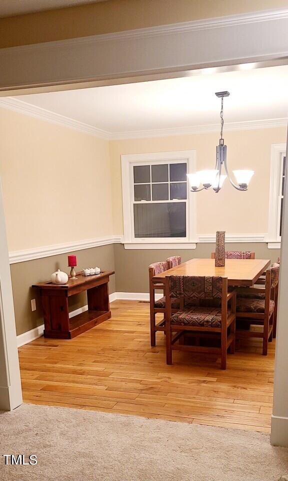 dining area featuring wood finished floors, an inviting chandelier, and crown molding