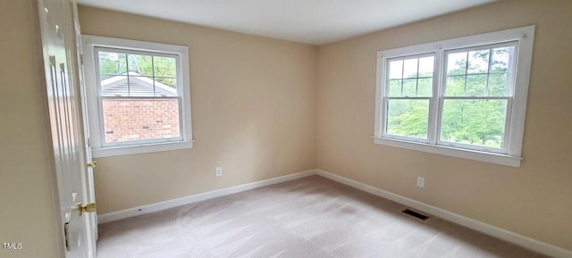 spare room featuring light carpet, baseboards, and visible vents