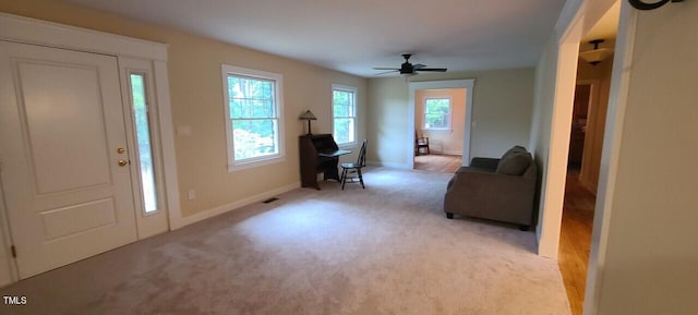 entryway with baseboards, a ceiling fan, and light colored carpet