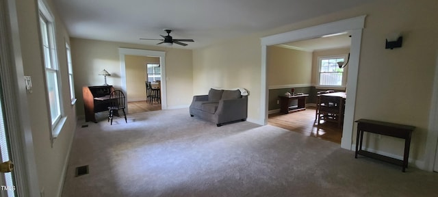 sitting room with baseboards, visible vents, a ceiling fan, and light carpet