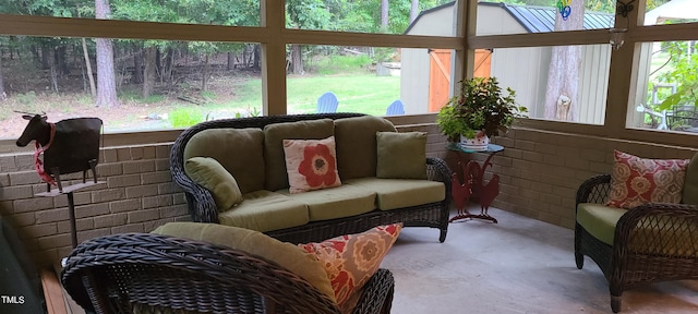 sunroom / solarium with concrete floors, an outdoor hangout area, and brick wall