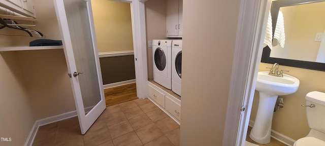 washroom with independent washer and dryer, cabinet space, baseboards, and light tile patterned floors