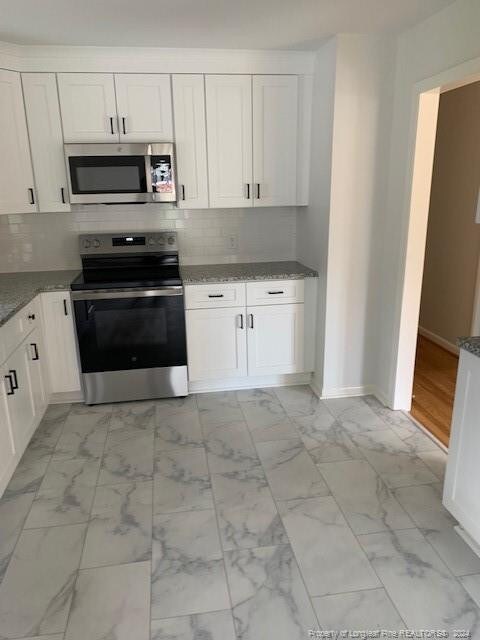 kitchen featuring appliances with stainless steel finishes, backsplash, and white cabinetry