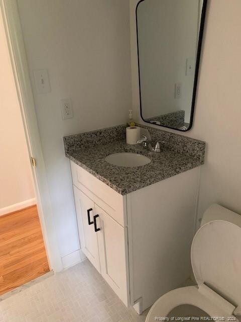 bathroom with wood-type flooring, vanity, and toilet