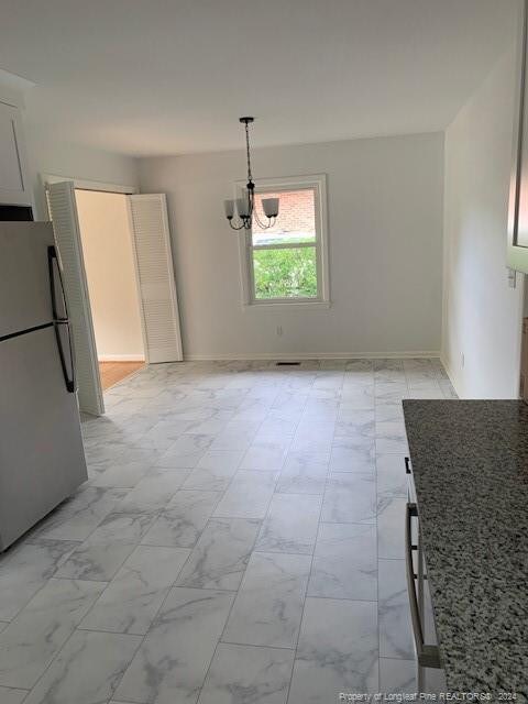 unfurnished dining area with a notable chandelier