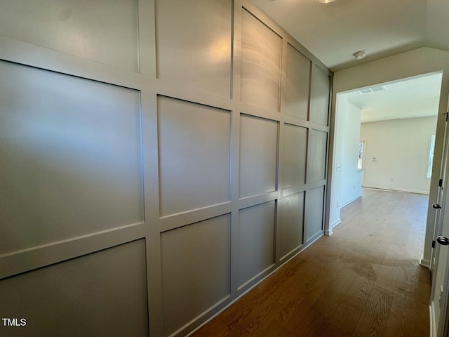 hall featuring dark wood finished floors, visible vents, and a decorative wall