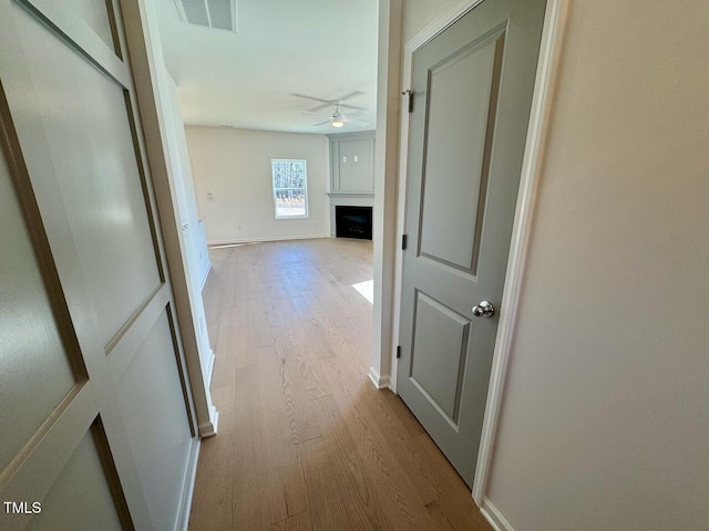 hall with baseboards, visible vents, and wood finished floors