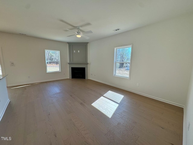 unfurnished living room with a fireplace, baseboards, and wood finished floors