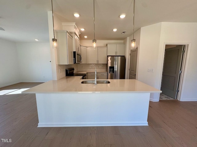 kitchen with wood finished floors, stainless steel appliances, a sink, and light countertops