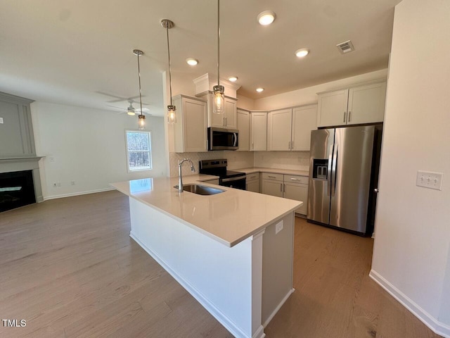 kitchen with light countertops, visible vents, appliances with stainless steel finishes, a sink, and a peninsula