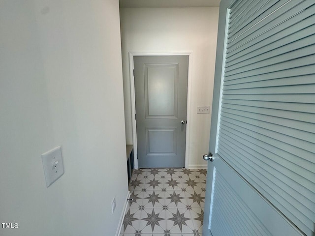 corridor featuring light floors and baseboards