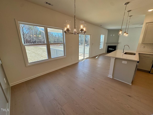 kitchen with visible vents, open floor plan, wood finished floors, a fireplace, and a sink