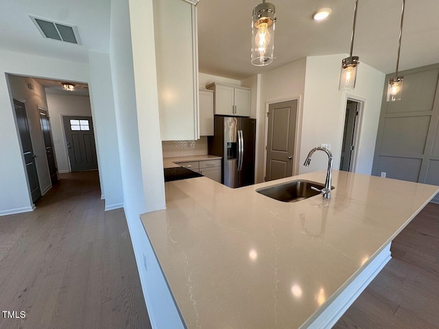 kitchen with wood finished floors, stainless steel refrigerator with ice dispenser, a sink, and visible vents