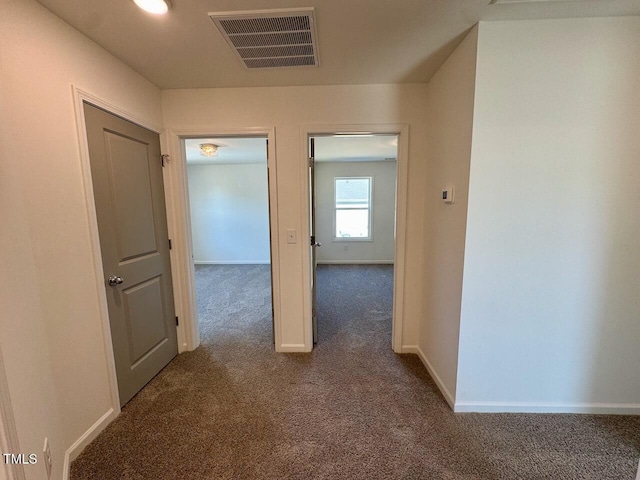 hallway featuring baseboards, visible vents, and carpet flooring