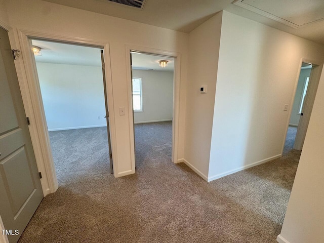 corridor with carpet floors, attic access, and baseboards