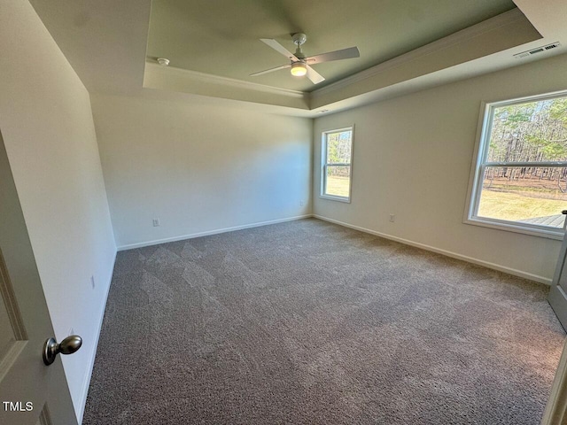 carpeted empty room with a tray ceiling, visible vents, ceiling fan, and baseboards